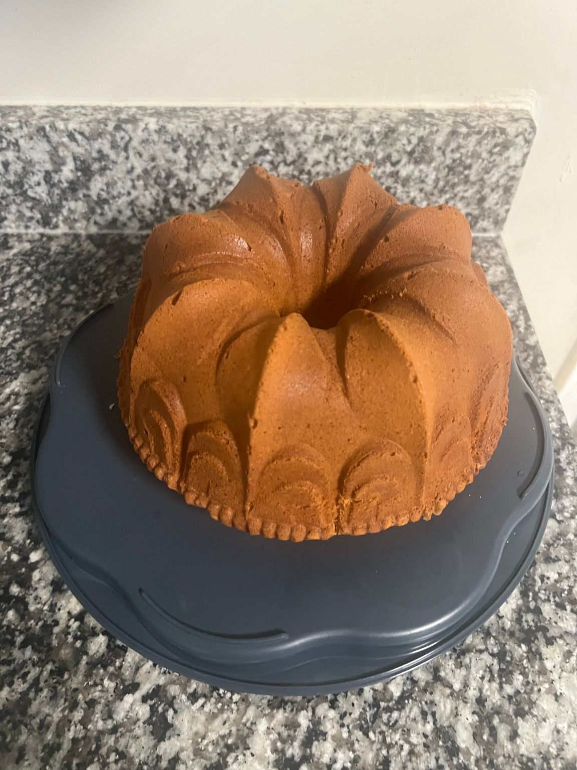 Golden brown bundt-style pound cake on a dark cake stand